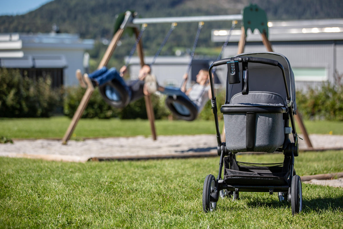 Stroller with the Sleepytroll Baby Rocker at a playground while older children play on the swings