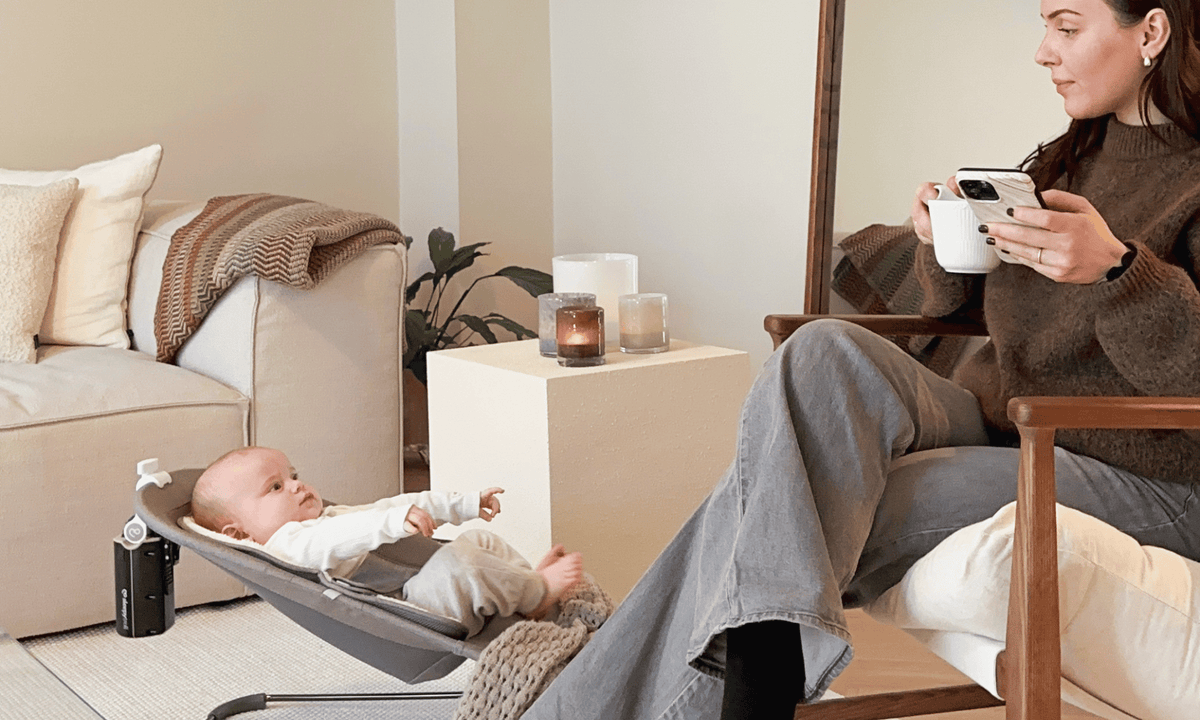 Mum enjoying a cup of coffee while Sleepytroll rocks her baby in a bouncer