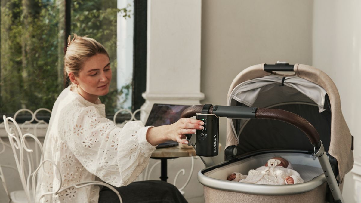Newborn baby safely sleeping in bassinet stroller being rocked by Sleepytroll Stroller Rocker
