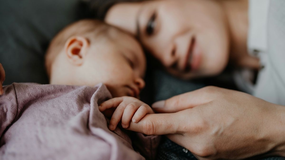 Mother holding her babys hand while baby is sleeping